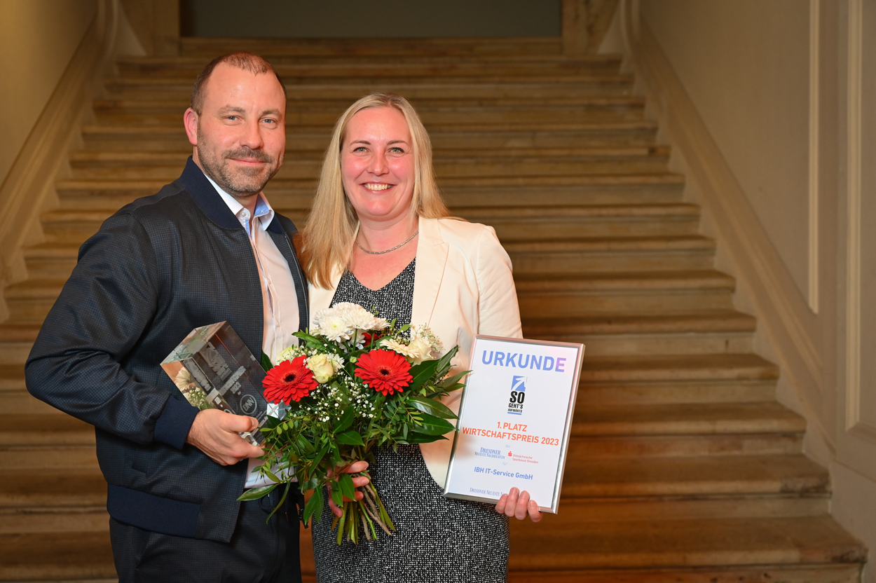 2023 wurden wir mit dem 1. Platz des DNN Wirtschaftspreises ausgezeichnet. Herr und Frau Zander mit einer Urkunde, dem Glaspreis und einem Blumenstrauß nach der Verleihung des DNN Wirtschaftspreises 2023